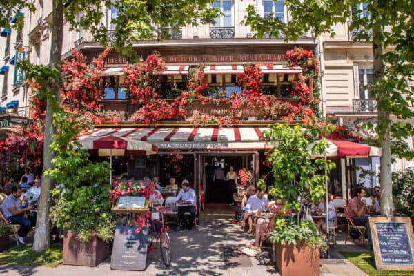 People sitting outside a pretty cafe surrounded by plants in Paris