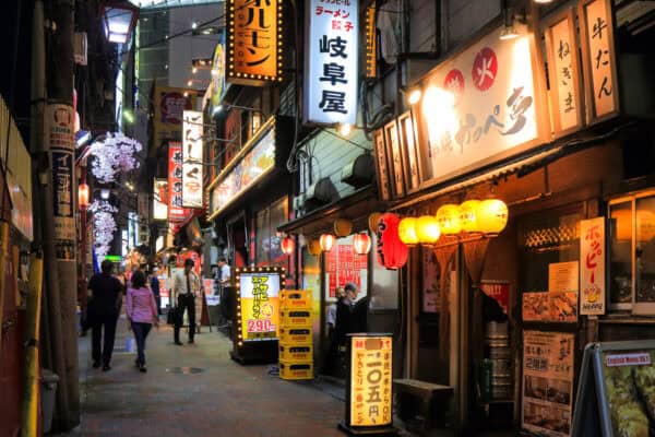 small aleyway in tokyo lit up and filled with bars