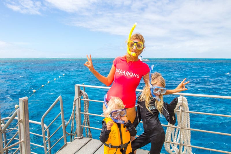 woman and children with snorkels on posing on boat