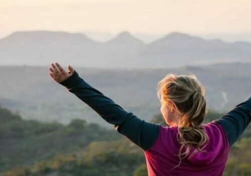girl with arms outstretched looking at mountain view