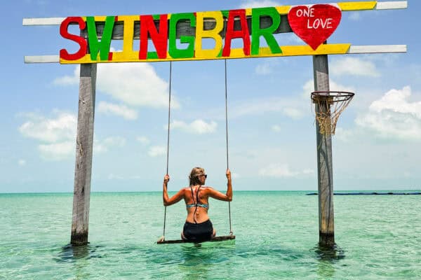 lady on swing in water at swing bar secret beach belize