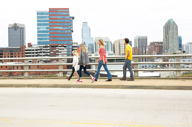 family crossing boylan bridge with raleigh skyline in background