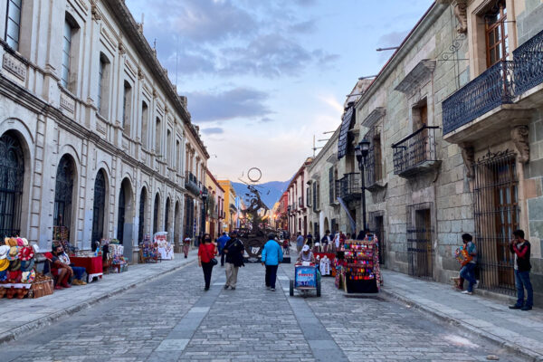 People walking down a street in Oaxaca, Mexico surrounded by buildings